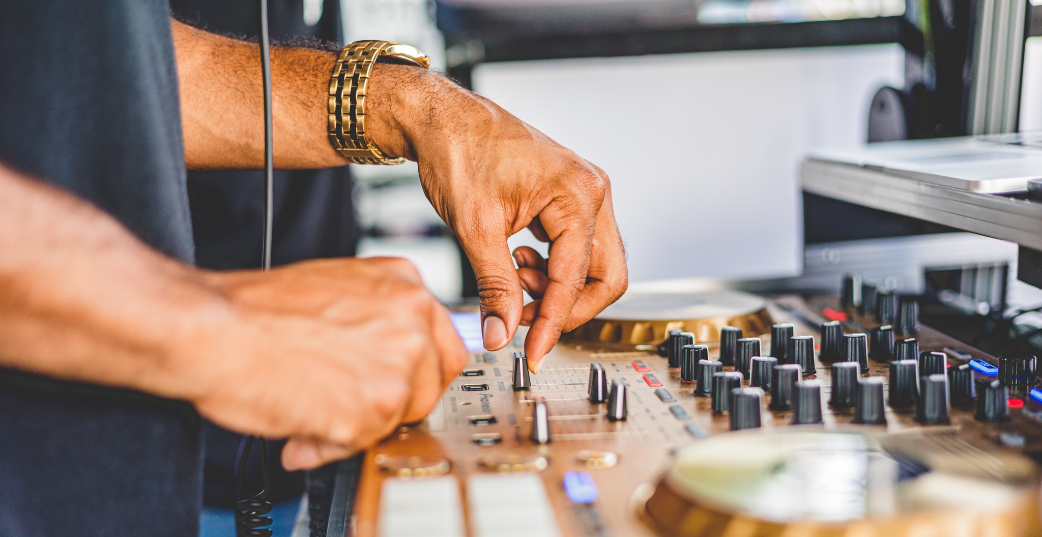 DJ mixing at an event while wearing a gold watch