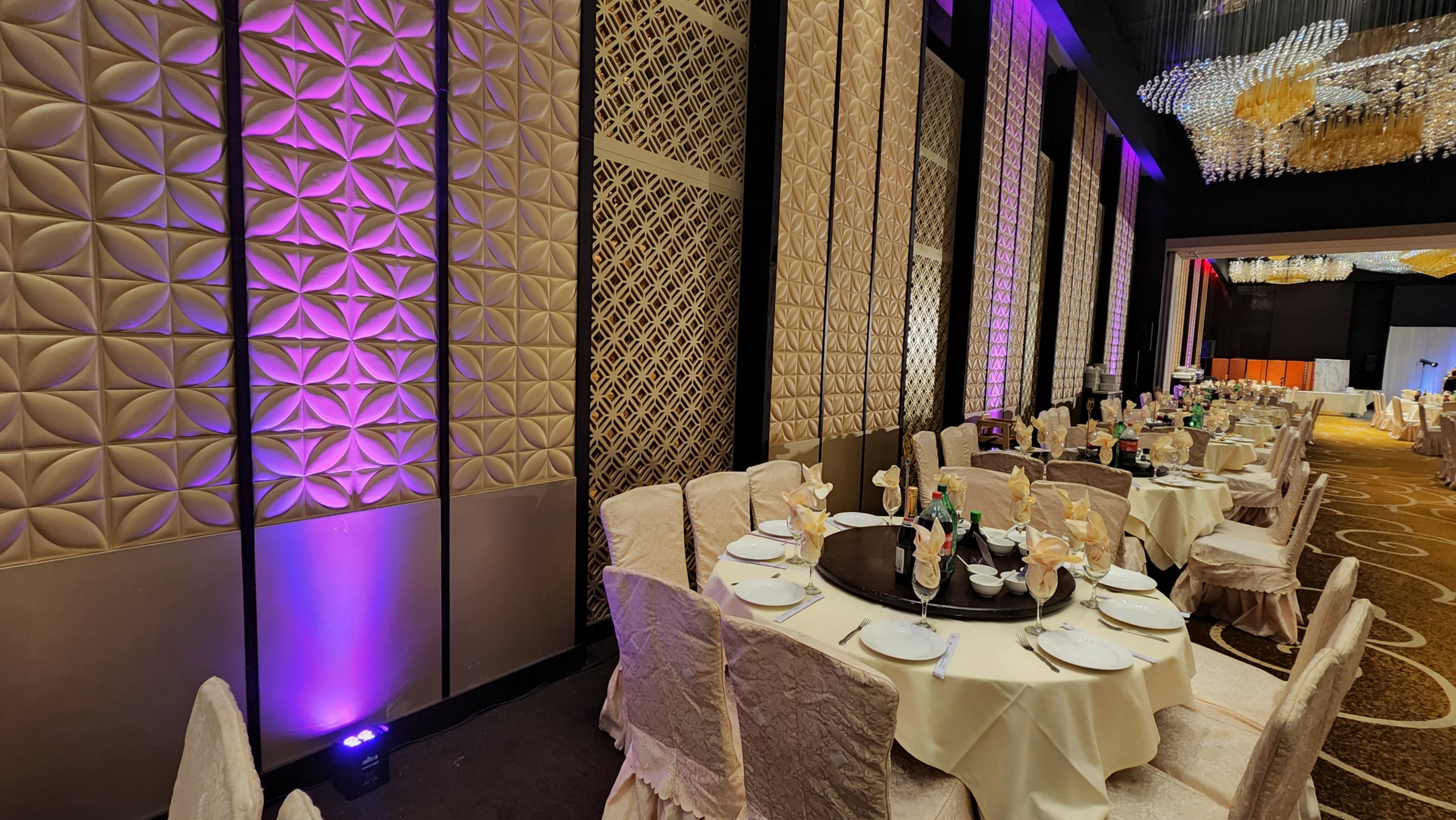 Purple uplighting transforming an elegant wedding reception room